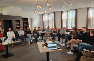 Groep mensen in zaal die luisteren naar presentatie